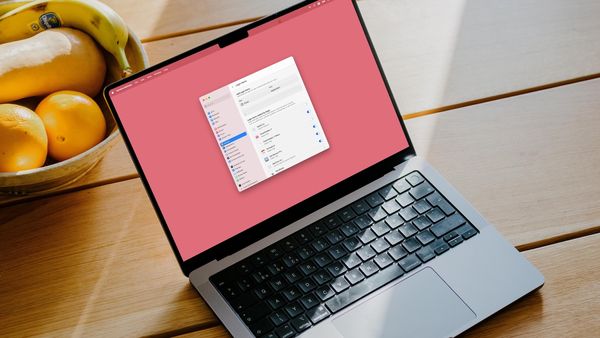 MacBook Pro 14-inch on wooden table with a bowl of fruit next to it