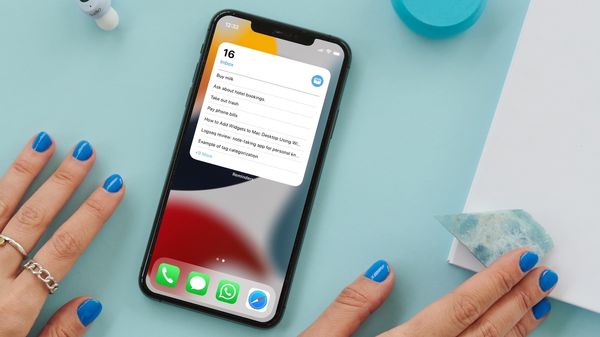 iPhone on blue table with hands on both sides showing reminders widget