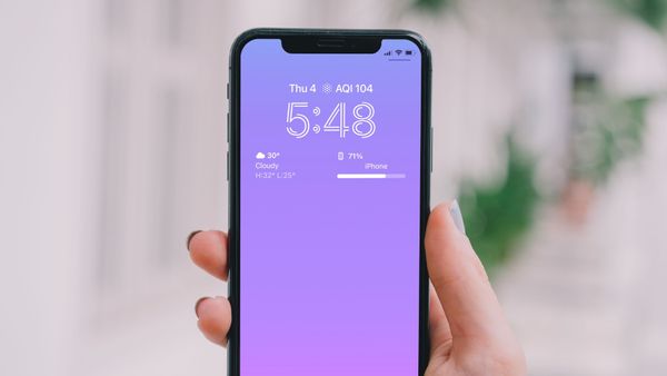 iPhone in Hand with bokeh background showing battery percentage on Lock screen