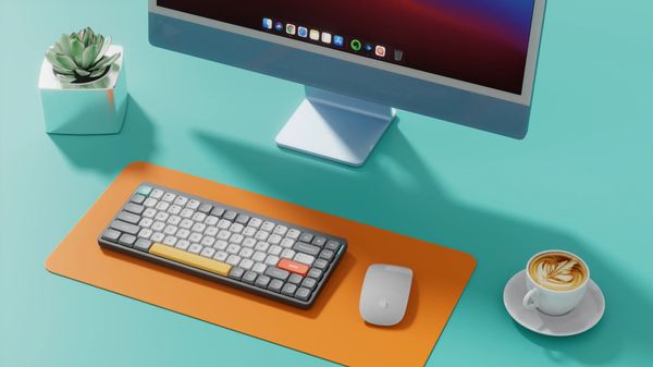 low profile mechanical keyboard on mouse pad with iMac 24-inch table and a coffee cup beside it
