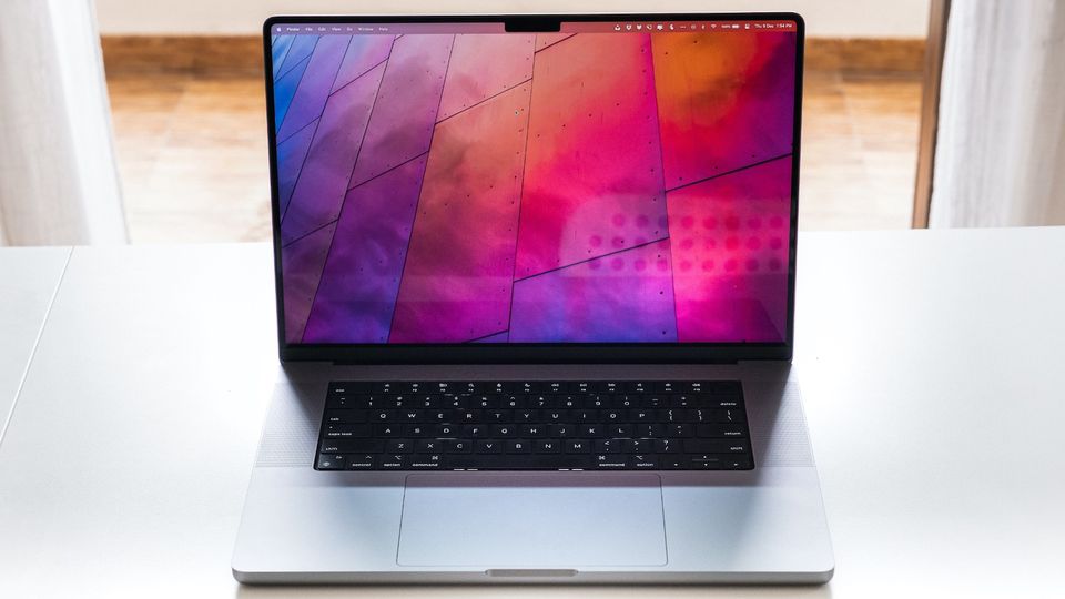 Silver MacBook Pro 16-inch on white desk with window as background