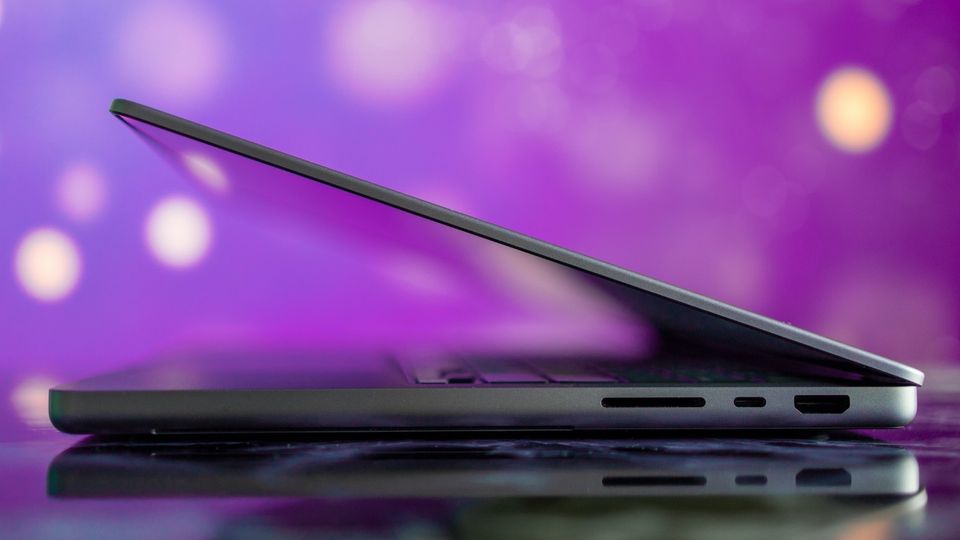 14-inch MacBook Pro with half open lid with bokeh purple background