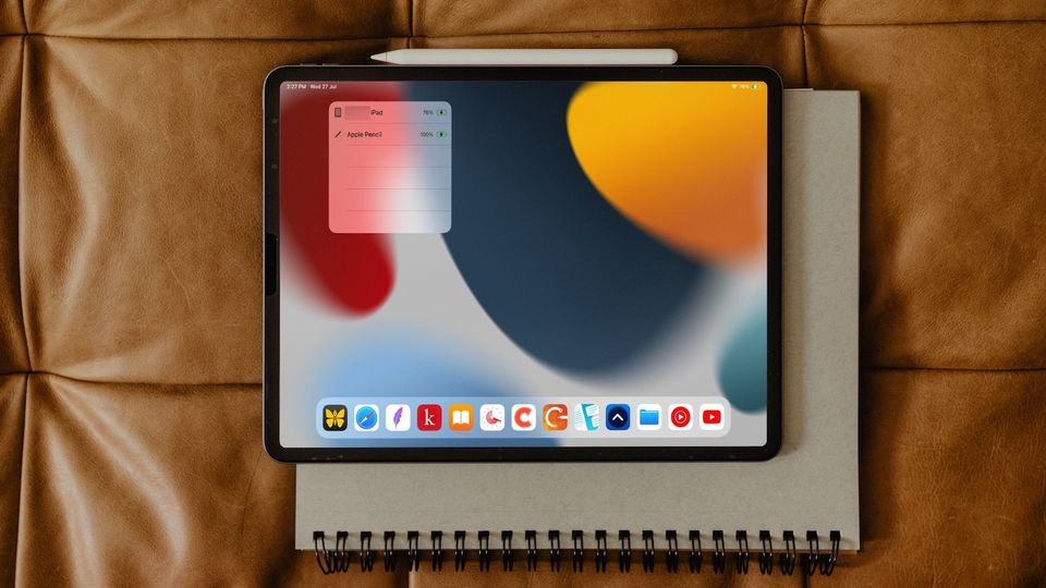 iPad Pro on top of notebook showing Apple Pencil charging and battery status