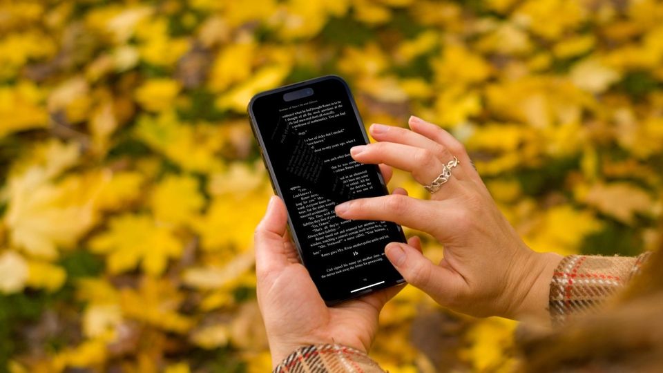 iPhone with Books app in girl hand with autumn background